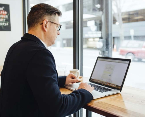 Man working on a laptop in a cafe, CampusCE Blog, What can data do for you?