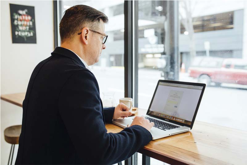 Man working on a laptop in a cafe, CampusCE Blog, What can data do for you?